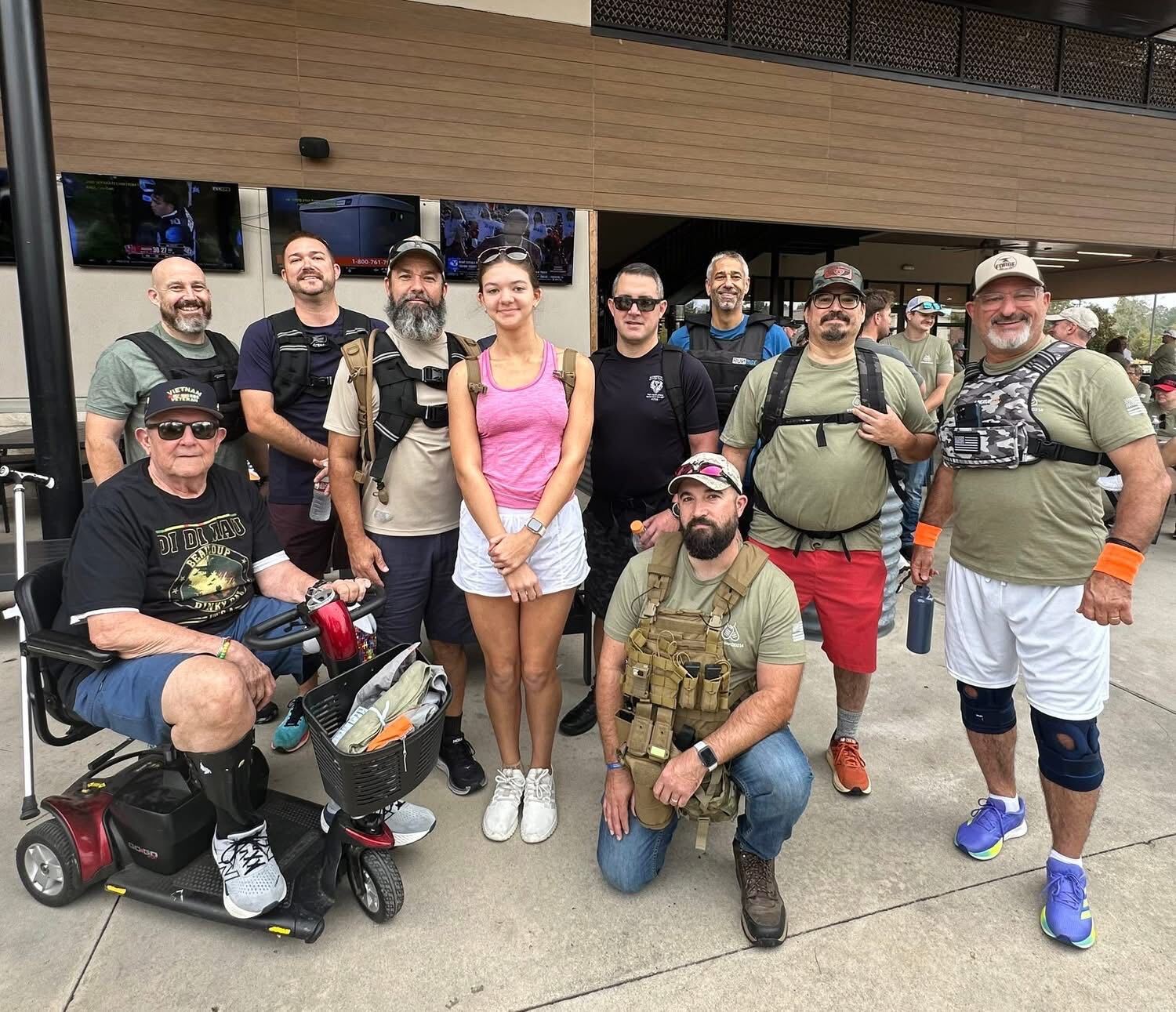 Veterans and ruckers posing together, including a Vietnam veteran on a mobility scooter