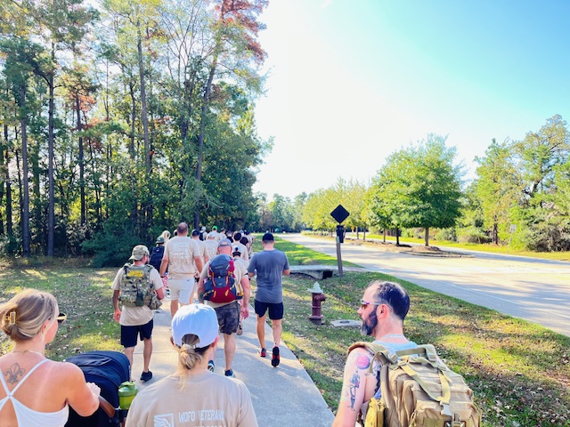 Walkers with packs along a tree-lined stretch of the ruck route