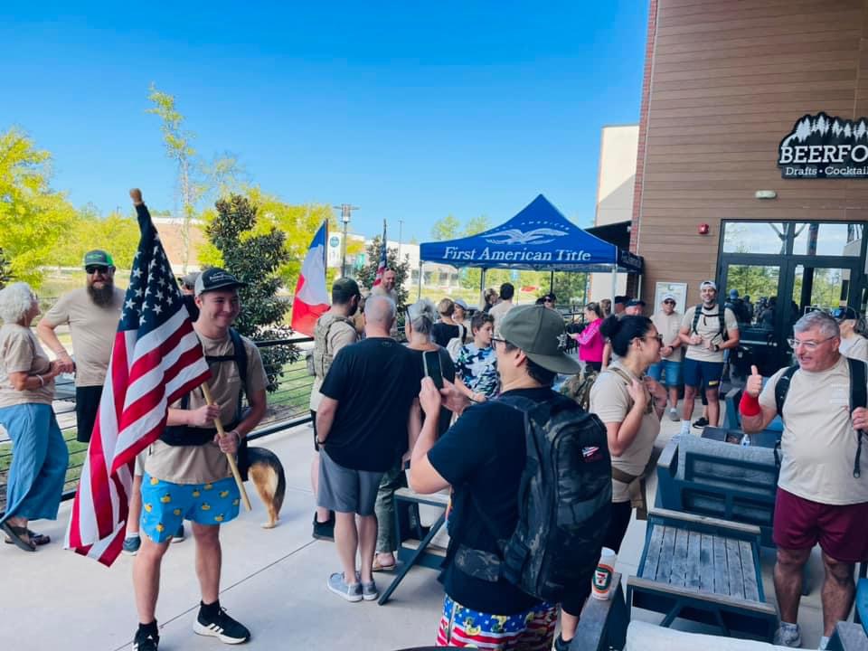Ruckers gathering with the American and Texas flags before the Woodforest Veterans Day Ruck start