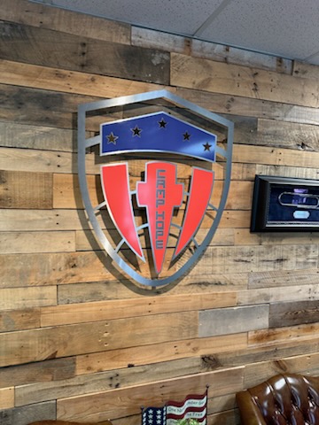 Woodforest Ruck metal shield emblem on a reclaimed wood wall